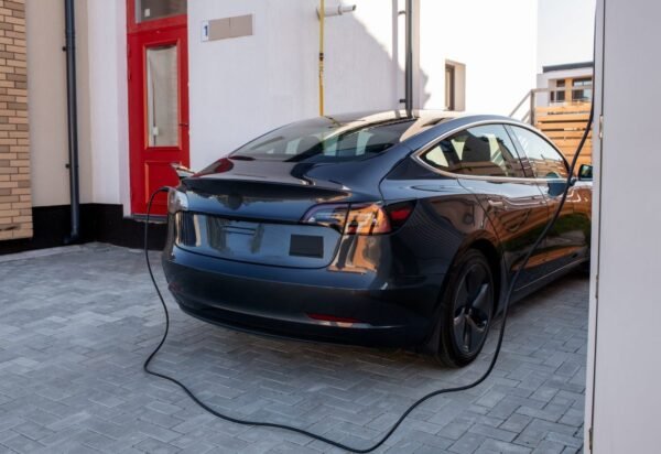 Black electric car is being charged at station Black electric car is being charged at station