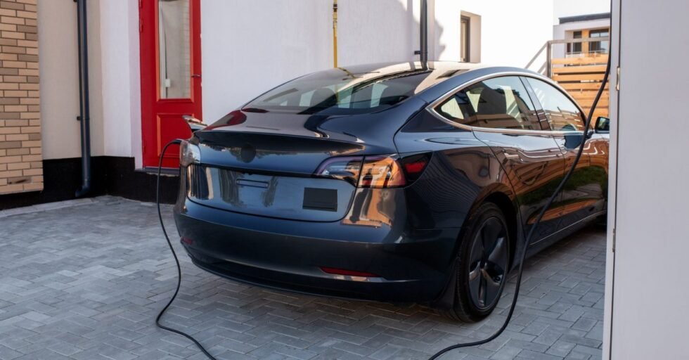Black electric car is being charged at station
