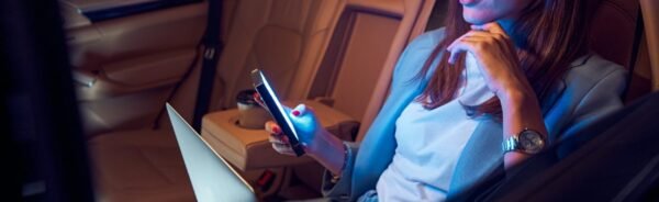 Woman using mobile phone and laptop in car