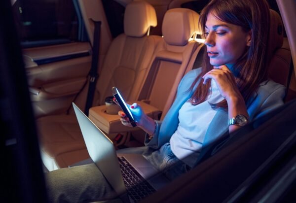 Woman using mobile phone and laptop in car Woman using mobile phone and laptop in car