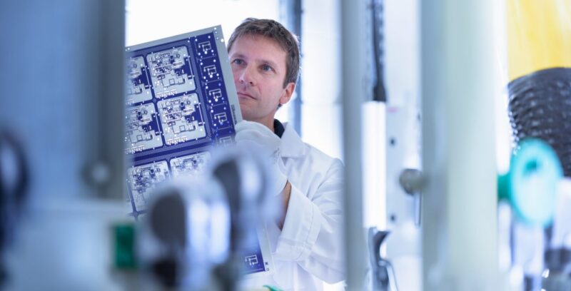Worker inspecting circuit board by processing plant in circuit board factory
