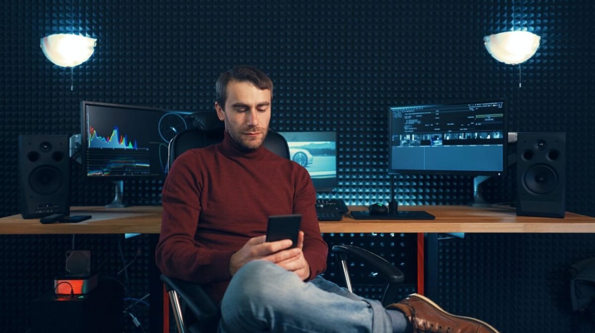 Young man working in the studio using a smartphone and computer.