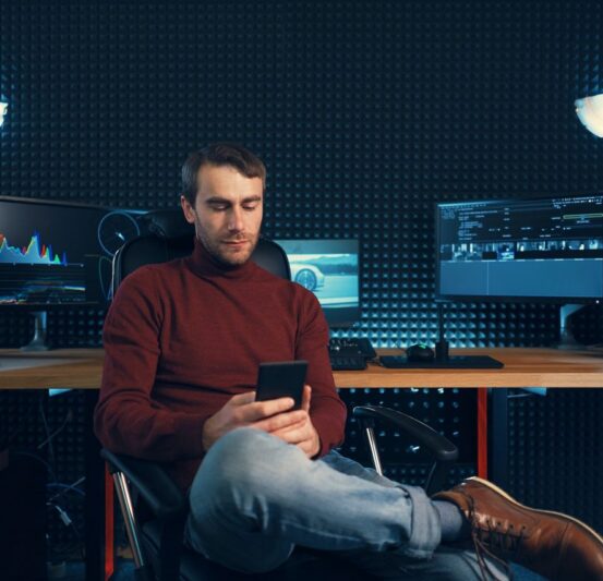 Young man working in the studio using a smartphone and computer. Young man working in the studio using a smartphone and computer.